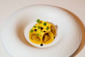 I tortelli di scorfano in zuppetta di frutti di mare con aglio nero e spuma di zafferano